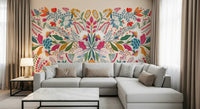 Frida's Garden wallpaper mural of symmetrical folk flowers behind a grey sectional sofa in a living room