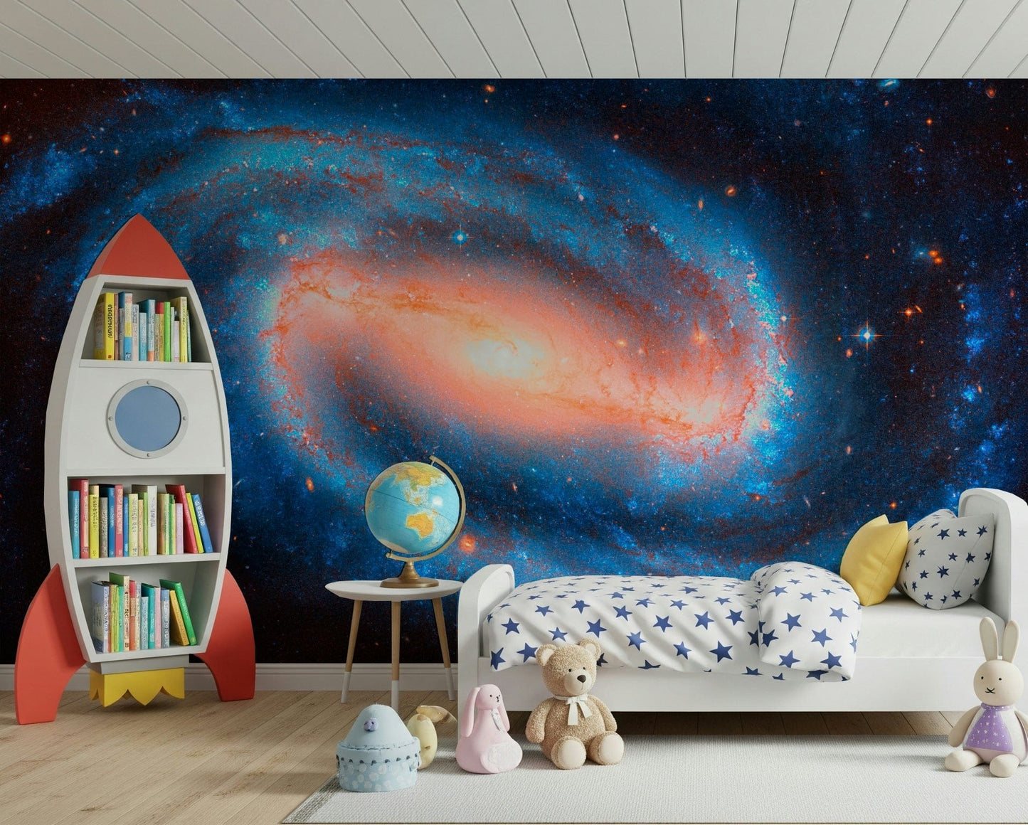 Galaxy Dream wallpaper mural of a blue and orange galaxy behind a white kids bed and red rocket bookshelf