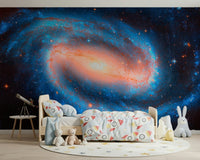 Galaxy Dream wallpaper mural of a spiral galaxy in a child's room with a wood bed, telescope and plush toys