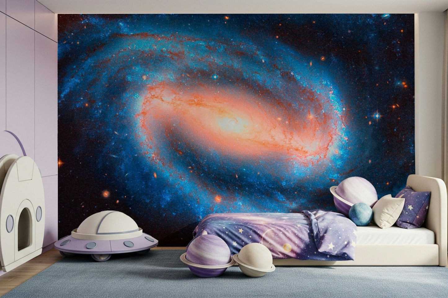 Galaxy Dream wallpaper mural of a deep blue galaxy in a child's room with a cream bed and purple UFO toy