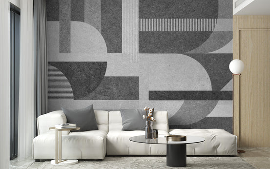Geometric Gray Grunge wallpaper with concrete-textured arcs and bars behind a white leather sofa in a living room