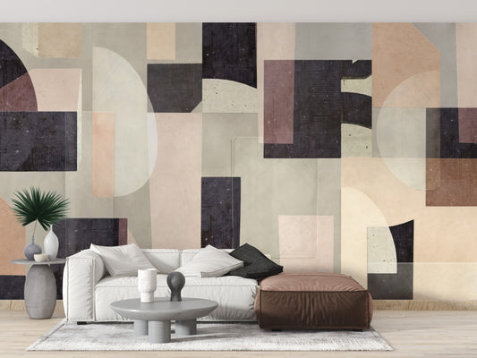 Modern Abstract wallpaper mural in earthy beige and charcoal geometric shapes behind a white sofa and brown leather pouf in a living room