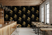 Ginkgo Luxury Gold wallpaper mural with gold ginkgo leaf sprays on black behind a wood bar and stools in a cafe