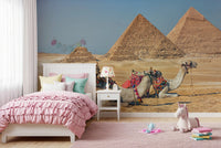 Giza wall mural of the pyramids and saddled camels in a girls room with a pink ruffled bed and unicorn plush