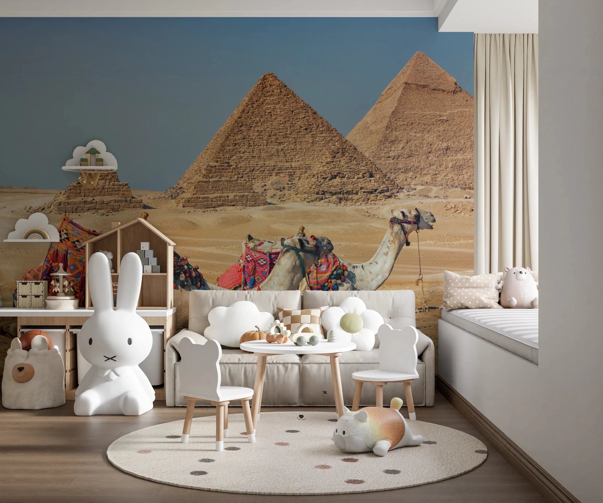 Giza wall mural of the pyramids and camels in a playroom with a white sofa, toddler table and bunny lamp