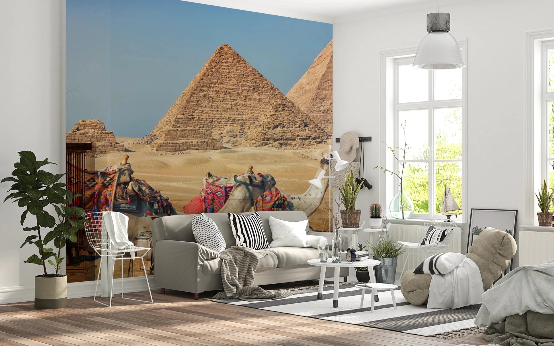 Giza wall mural of the pyramids and camels behind a grey sofa and white wire chairs in a living room