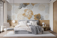 Gold Black Modern Floral wallpaper mural with gold and grey blooms on a pale wall behind a grey bed and woven chair