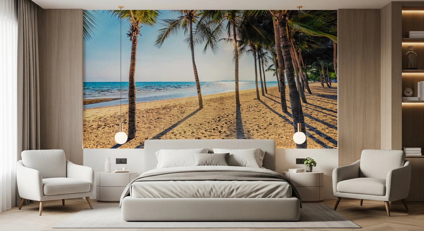 Golden Beach Palms wallpaper mural of palms and sea behind a grey bed flanked by cream armchairs