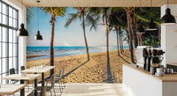 Golden Beach Palms wallpaper mural of a tropical beach in a cafe with black pendant lights and small tables