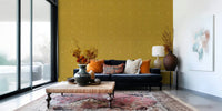 Golden Haze Texture wallpaper mural in mustard linen with white dots behind a navy sofa with orange cushions