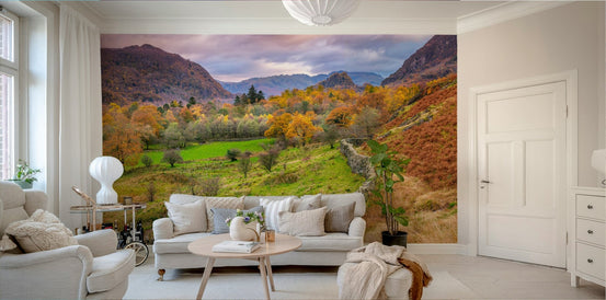 Golden Hills wallpaper mural of an autumn valley with green meadow and rugged hills at dusk behind a beige sofa in a living room