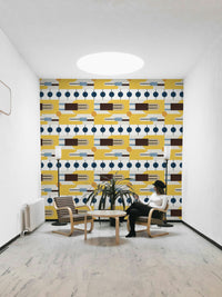 Golden Hour Hues wallpaper as a full-wall mural behind two wooden armchairs and a potted palm in a lounge