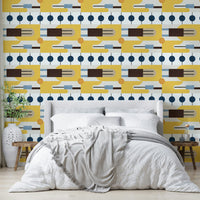 Golden Hour Hues wallpaper behind a grey upholstered bed with white bedding and an olive branch vase