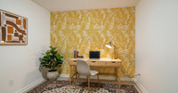 Golden Meadow Dream wallpaper in golden yellow foliage behind a wood desk and beige chair in a home office