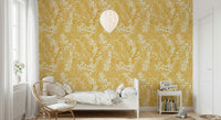 Golden Meadow Dream wallpaper in soft yellow leaves in a kids room with a white bed and rattan chair