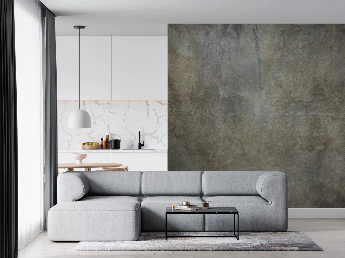 Golden Paper Collage wallpaper mural in mottled grey-green plaster behind a grey sectional in an open-plan living room