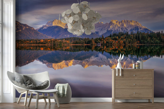Golden Peaks Reflection wallpaper mural of sunlit alps mirrored in a lake behind a white chair and wood dresser