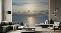 Reading nook wall mural with shimmering sea and warm sunset, cozy chair setup