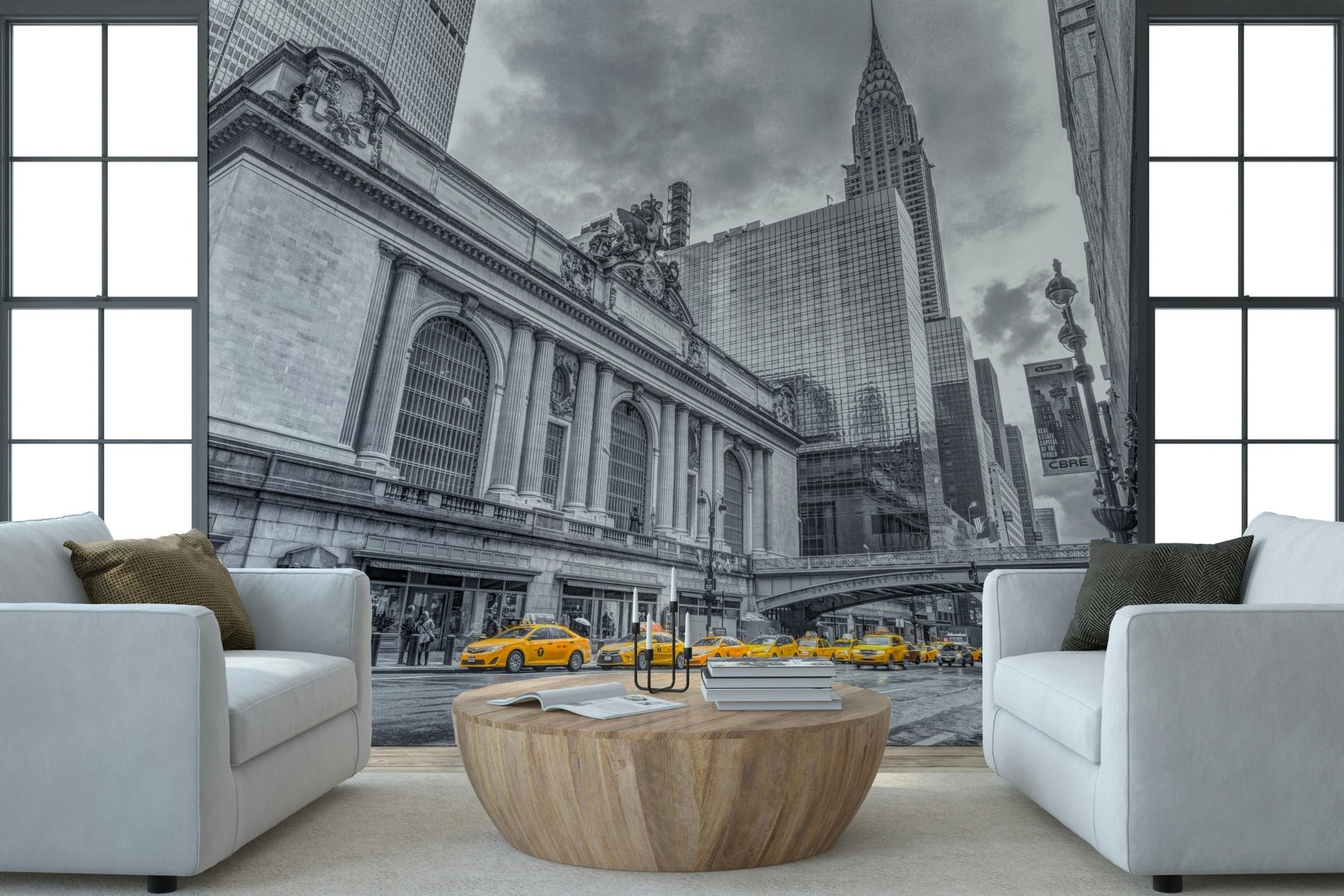Grand Central Terminal mural with yellow cabs framed by two white armchairs and a round wood coffee table