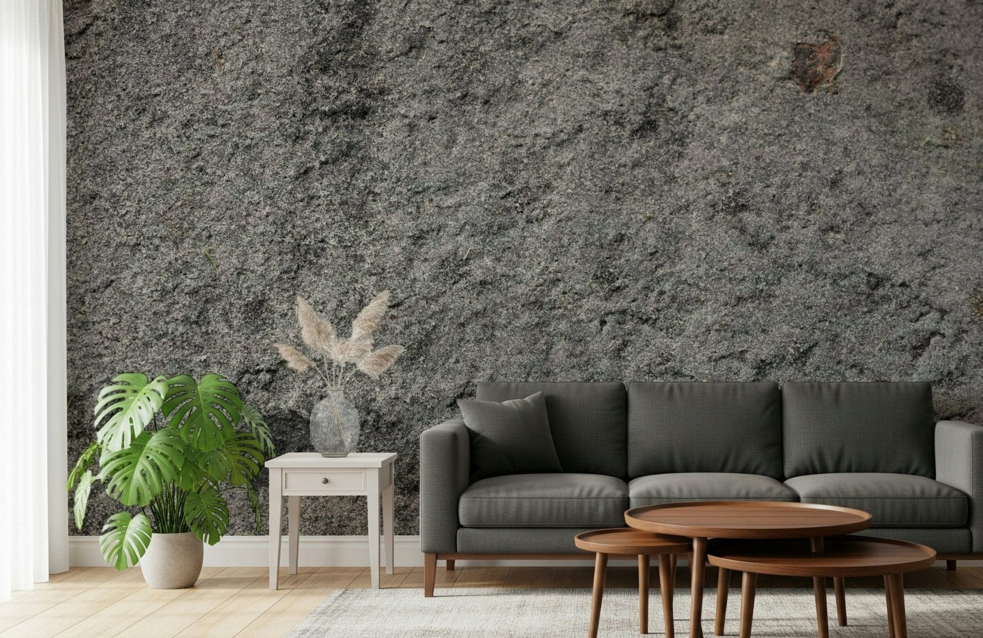 Granite Gray wallpaper mural behind a dark grey sofa, monstera plant and nesting walnut coffee tables