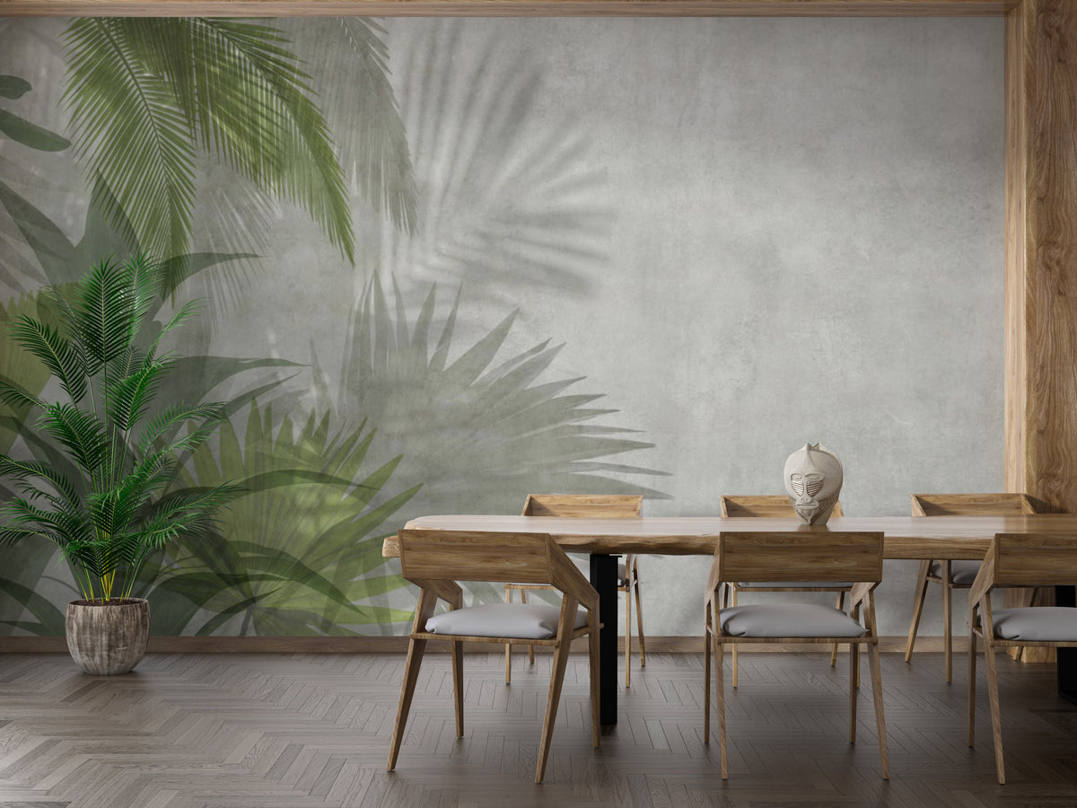 Green Leaves wallpaper mural of palm fronds on grey concrete in a dining room with wood table, chairs and a potted palm