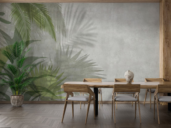 Green Leaves wallpaper mural of palm fronds on grey concrete in a dining room with wood table, chairs and a potted palm