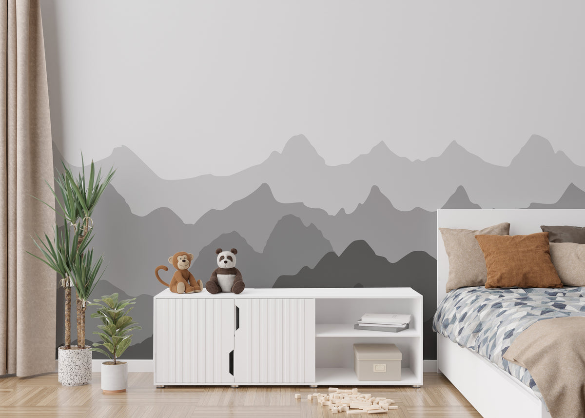 Grey Silhouettes Mountains wallpaper mural above a white bed and toy sideboard in a kids bedroom