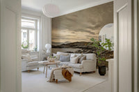 Dramatic wall mural of a lighthouse on a rocky coast with mountains in the distance.