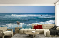 Hawaii Rocky Shore wallpaper mural of turquoise ocean waves and blue sky behind a beige sectional sofa in a living room