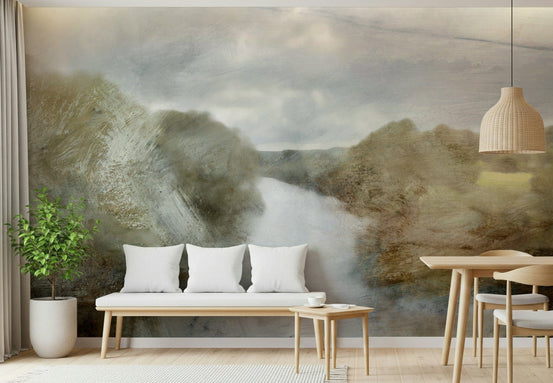 River Haze wallpaper mural of a misty river between olive hills behind a wood bench with white pillows in a living room