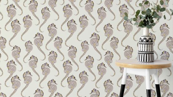 Hippocampus wallpaper with taupe seahorses on cream behind a white stool holding a striped vase and eucalyptus