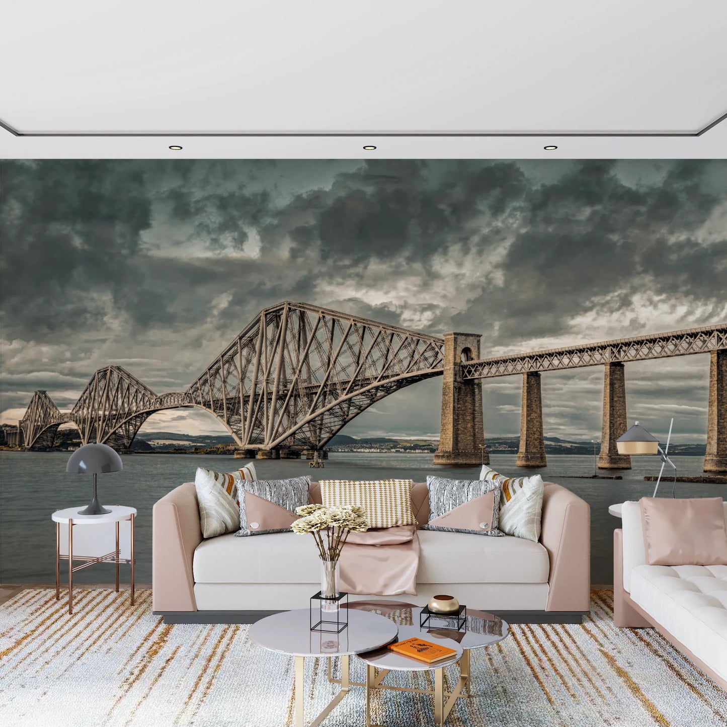 Historic Forth Rail Bridge wall mural with dramatic clouds behind a pale pink living room sofa