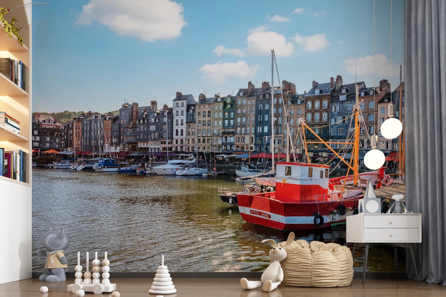 Honfleur Harbor Charm wallpaper mural of the harbor and red boat in a kids room with bookshelves and toys
