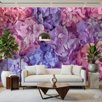 Hydrangea Hues wallpaper mural of purple and pink blooms behind a cream sofa with a chrome arc lamp in a living room