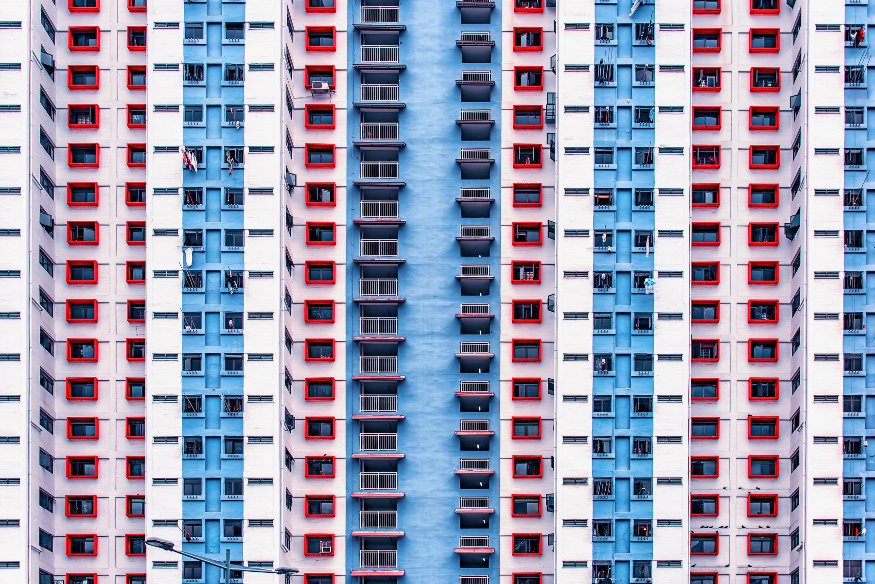 Urban Gridlock wallpaper mural of red and blue high-rise windows behind a white sofa in a modern living room