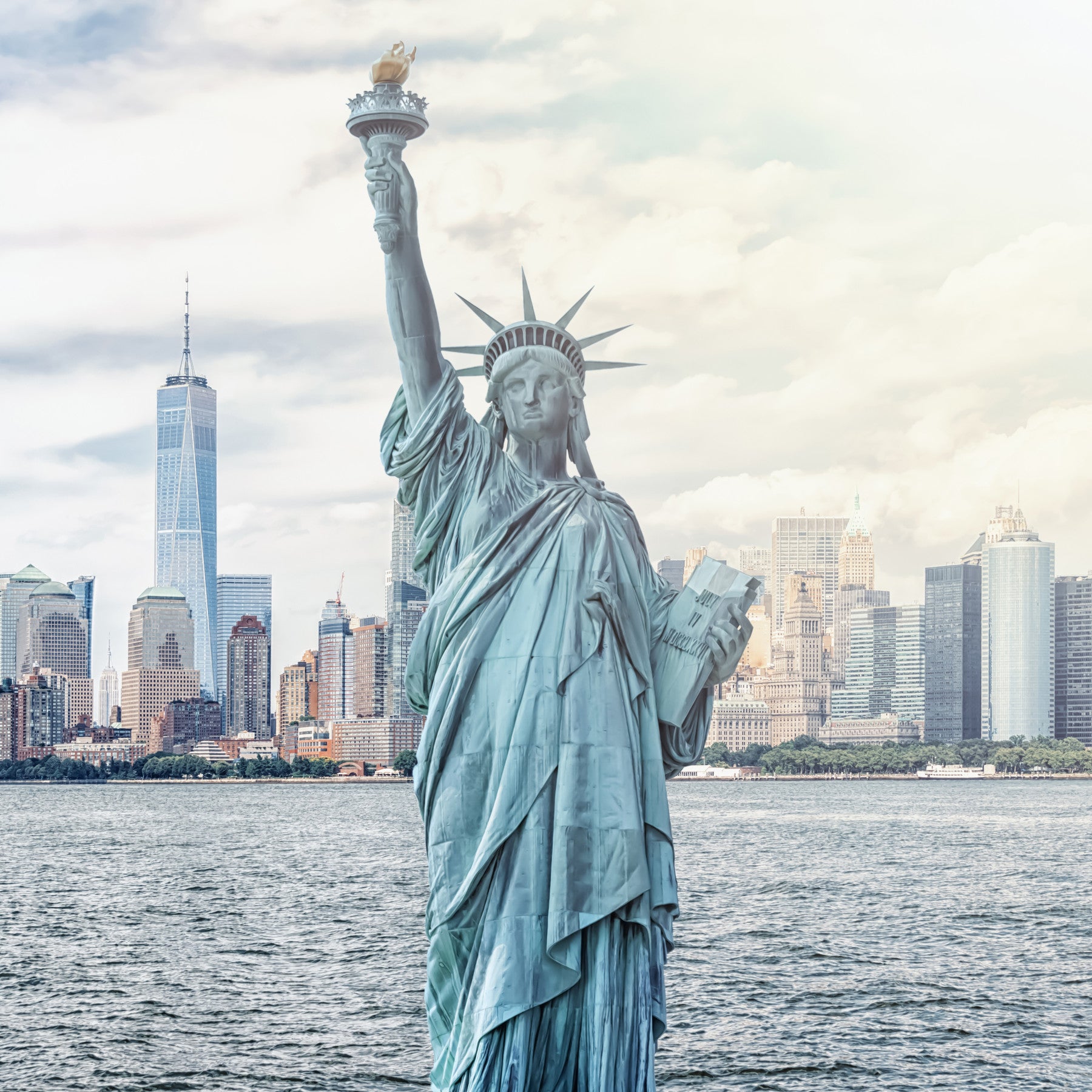 NYC's Lady Liberty wallpaper mural with the Statue of Liberty and skyline behind a wood bed with green bedding in a bedroom
