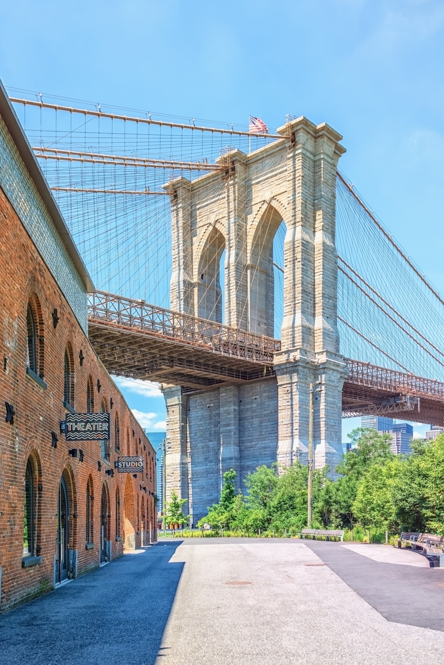 Brooklyn Bridge Vista wallpaper mural of the stone bridge tower and brick warehouse behind a grey sectional in a living room