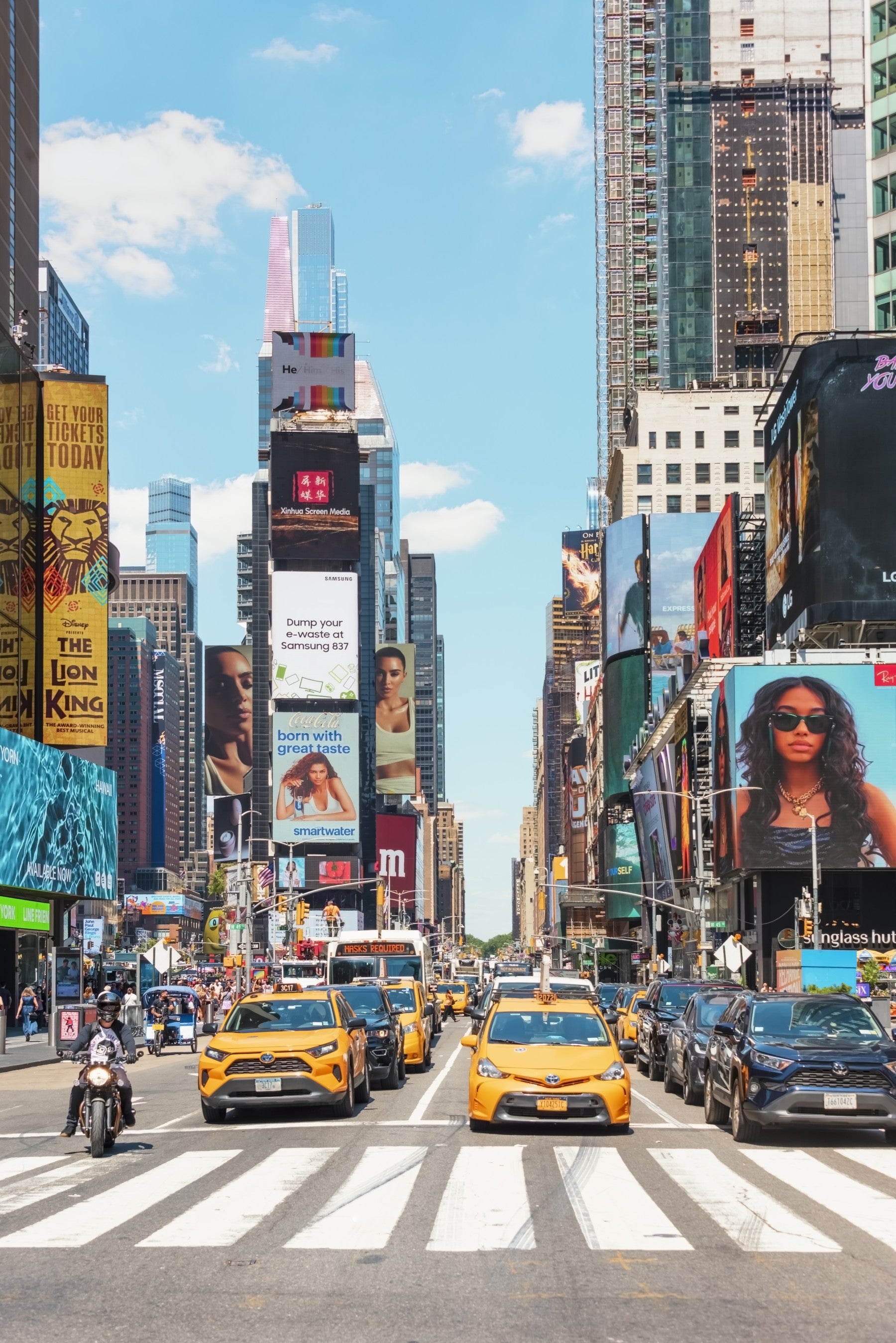 Times Square Buzz wallpaper mural of NYC billboards and skyscrapers behind a gray bed in a navy-paneled bedroom