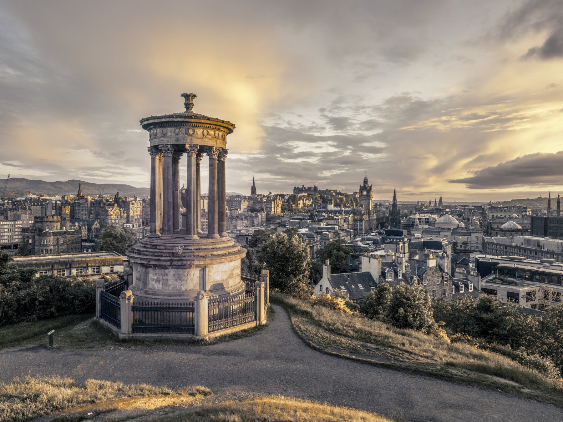 Scottish Skyline wallpaper mural of Edinburgh at sunset behind a blush sofa with round marble tables