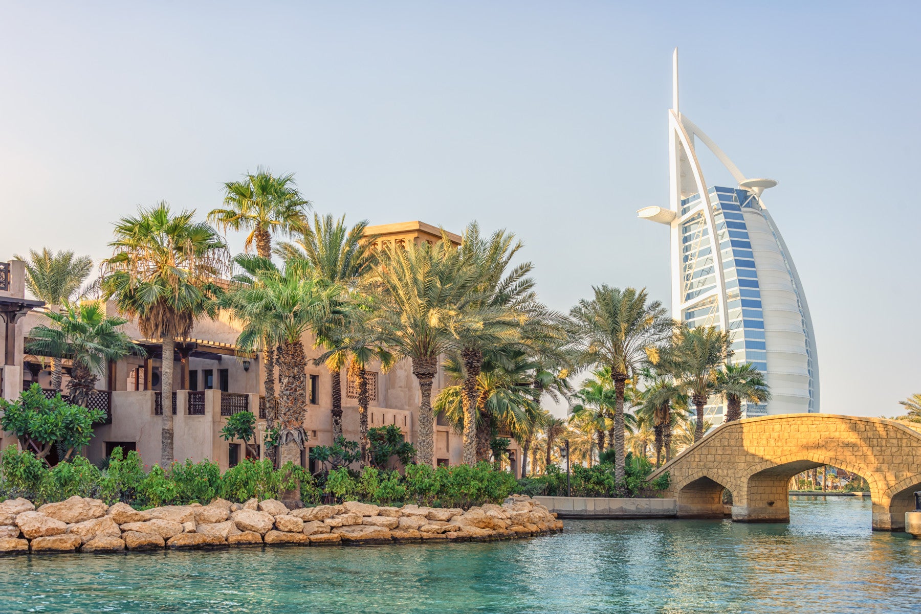 Dubai Oasis wallpaper mural of the Burj Al Arab and palms behind a beige tufted sofa in a living room