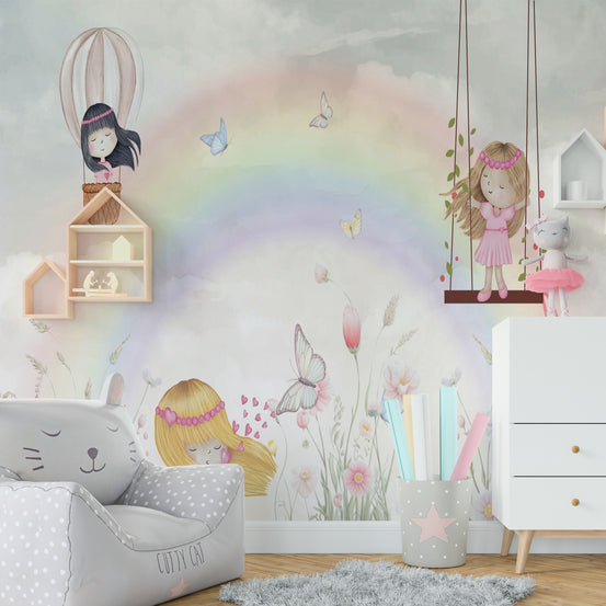 Little Girls Adventures wall mural with a pastel rainbow and fairies above a gray cat beanbag chair in a kids room