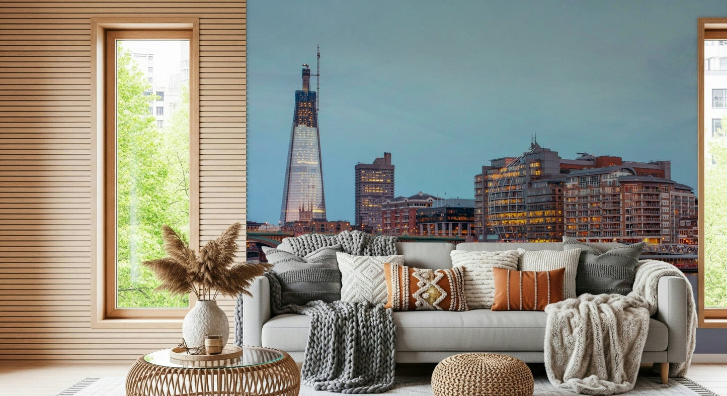 London Luminescence wallpaper mural of the lit London skyline above a white sofa with knit and orange pillows