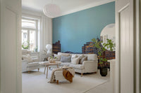 London Luminescence wallpaper mural in blue tones behind white sofas and a fiddle-leaf fig in a bright living room