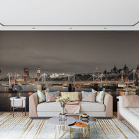 London's Nightfall wallpaper mural of the glowing London skyline behind a blush sofa and round marble tables