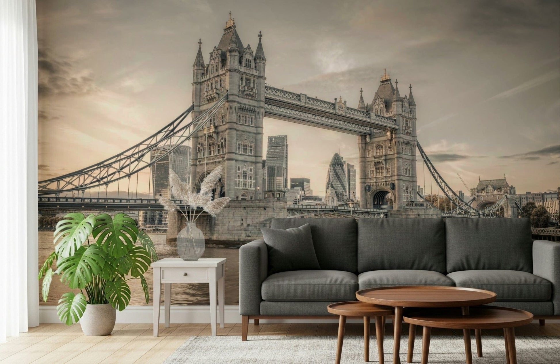 London's Tower Bridge wallpaper mural in sepia behind a dark grey sofa with a big monstera plant