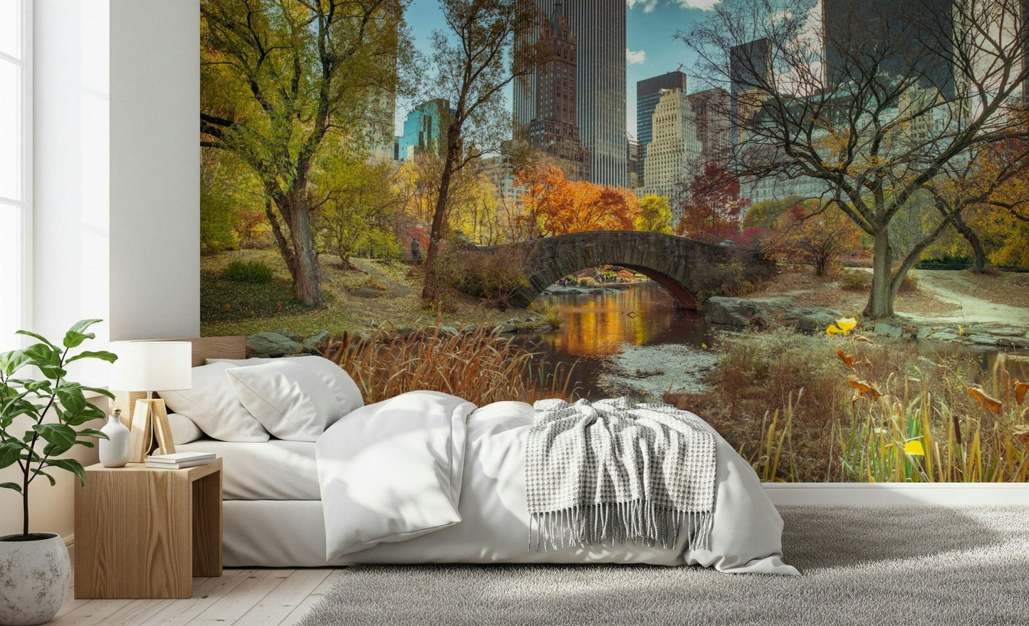Manhattan's Autumn Embrace wallpaper mural of an autumn park behind a white bed and wood nightstand in a bedroom