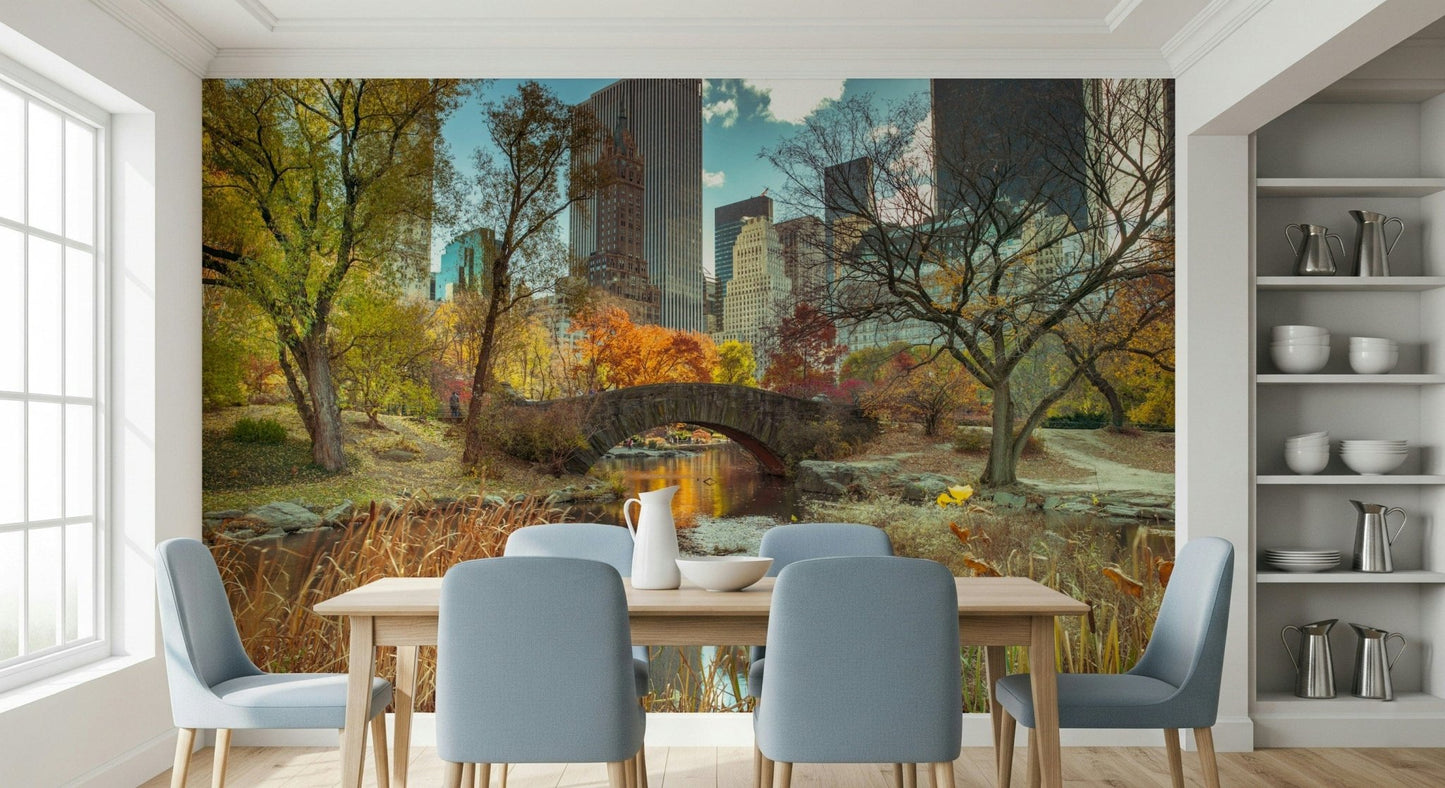 Manhattan's Autumn Embrace wallpaper mural of Central Park in fall behind a wood dining table and blue chairs