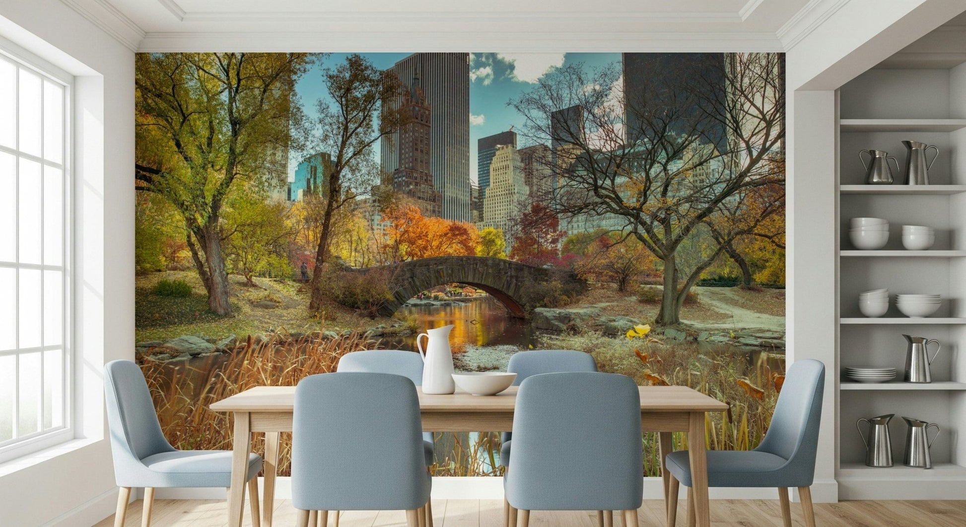 Manhattan's Autumn Embrace wallpaper mural of Central Park in fall behind a wood dining table and blue chairs