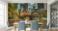 Manhattan's Autumn Embrace wallpaper mural of Central Park in fall behind a wood dining table and blue chairs