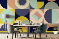 Mescolanza Alt V3 wallpaper mural in navy, mustard and sage geometric shapes behind a round wood dining table and grey chairs